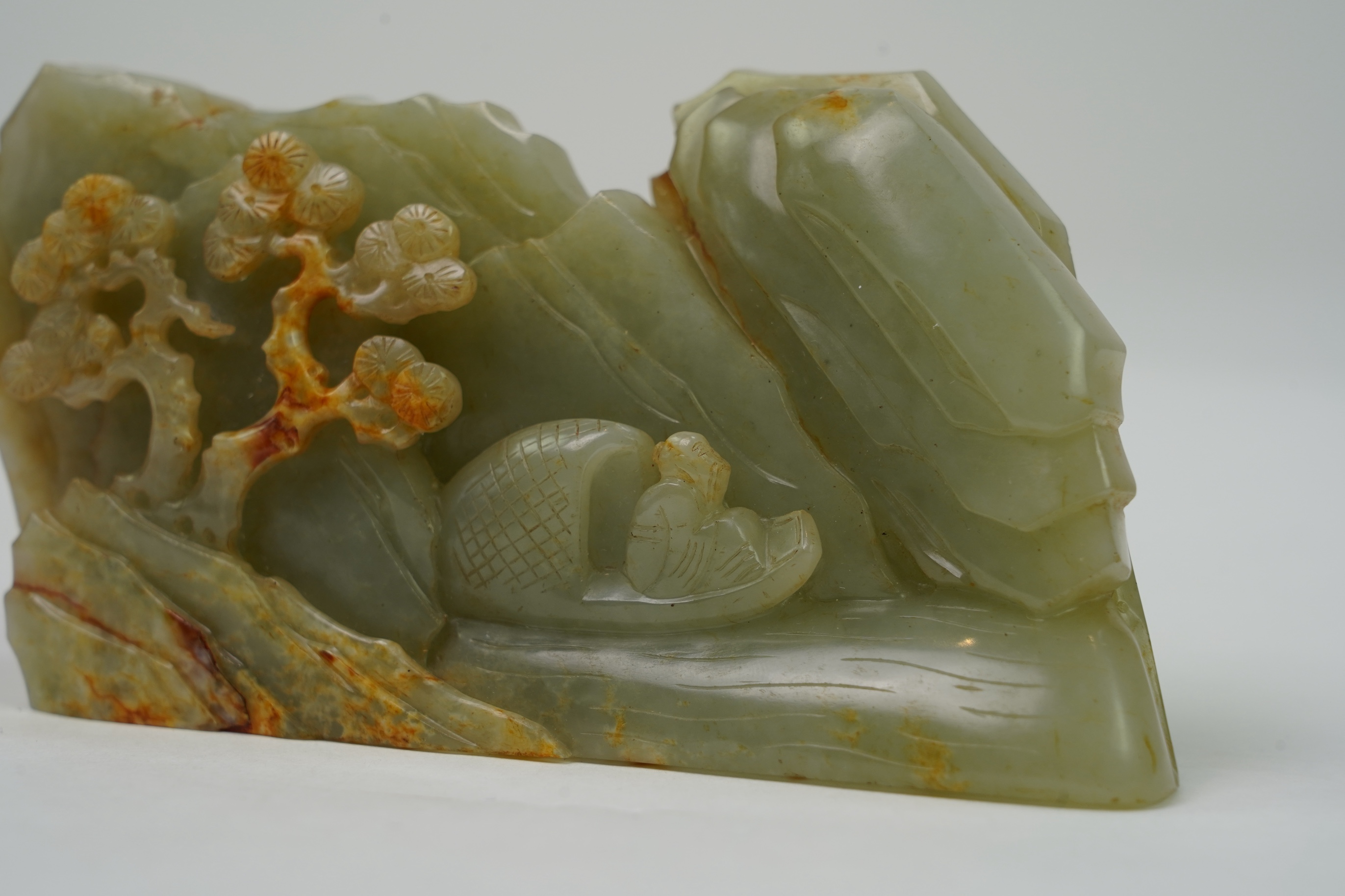 A Chinese celadon and russet jade boulder carving